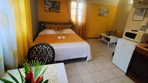 A hotel room with a bed, a desk, a chair, a microwave, and a small refrigerator. - Bungalow Saphir Idéal Pour Amoureux à 2 Minutes de la Plage, en Bord de Piscine! (Sainte-Rose)