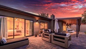 Ein modernes Haus mit einer Terrassenanlage, die eine Couch, eine Holzbank und einen Hängesessel bietet.