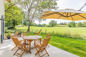 An outdoor patio with a round wooden table and chairs, a large yellow umbrella, and a hammock. - la Randonneuse - Berze LE Chatel (BERZE LE CHATEL)