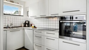 Eine moderne Küche mit weißen Schränken, einem Edelstahlbackofen und einer Kaffeemaschine.