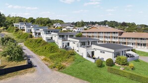 Ein modernes Wohngebiet mit mehreren zweistöckigen Häusern, einem gepflasterten Weg und gepflegten Rasenflächen.