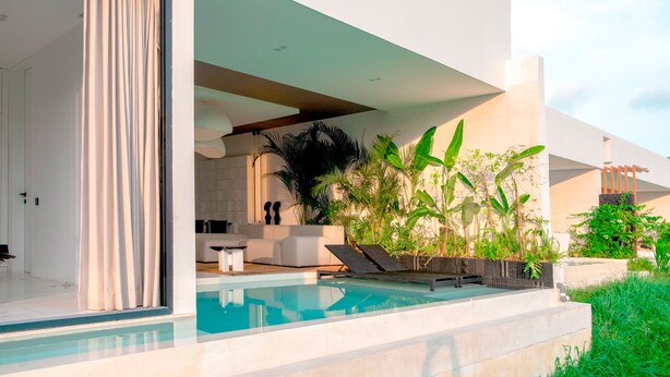 A modern outdoor pool area with a minimalist design, including a seating area and lush greenery. - Green Flow Villa 3 (Ubud)