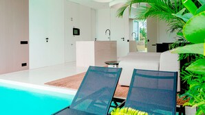 A modern indoor pool area with lounge chairs, a sofa, and a small table. - Green Flow Villa 3 (Ubud)