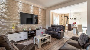 A modern living room with a stone wall, leather sofa, and a flat-screen TV. - Beautiful home in Polaca (Polaca)