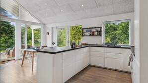 A modern kitchen with white cabinets, a black countertop, and a large window overlooking a garden. - Stunning home in Jægerspris with WiFi (Jægerspris)