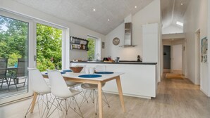 A modern kitchen with a central island, white cabinetry, and a large window overlooking greenery. - Stunning home in Jægerspris with WiFi (Jægerspris)