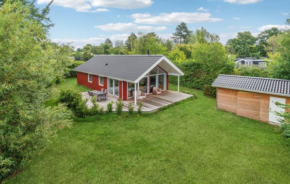 Ein rotes Haus mit einer großen Terrasse und Schiebetüren.