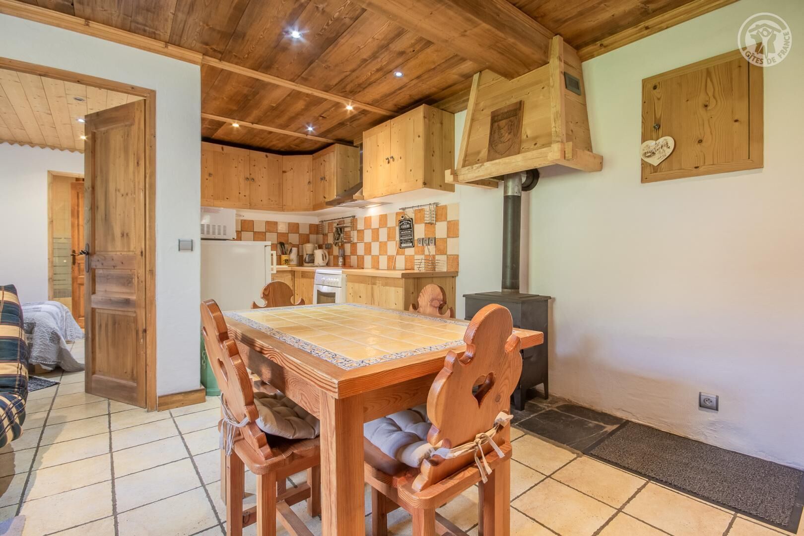 Un intérieur chaleureux en bois, avec une table à manger, des chaises, un coin cuisine et une cheminée.