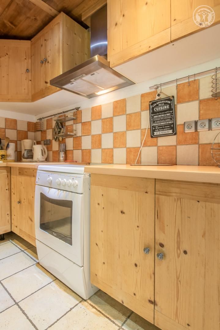Une cuisine avec des armoires en bois, un four blanc et un dosseret à carreaux.