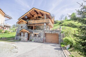 Une maison en pierre à deux étages, dotée d’un balcon en bois, d’un garage et d’une allée.