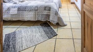 Une chambre confortable avec un plafond en bois, un lit avec une literie à motifs, une fenêtre avec des rideaux et un lave-linge dans la pièce adjacente.