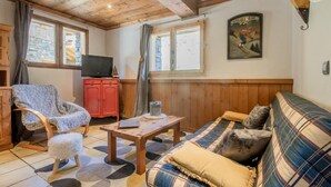 Un salon chaleureux avec un canapé à carreaux, une table basse en bois et un meuble rouge.