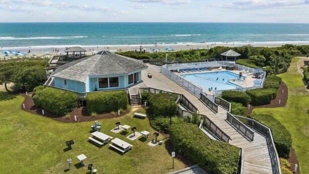 A coastal property with a large swimming pool, a gazebo, and a beach view. - First Floor Pebble Beach
3BR/2BA Oceanview Condo 
Steps from the Beach
 (Emerald Isle)