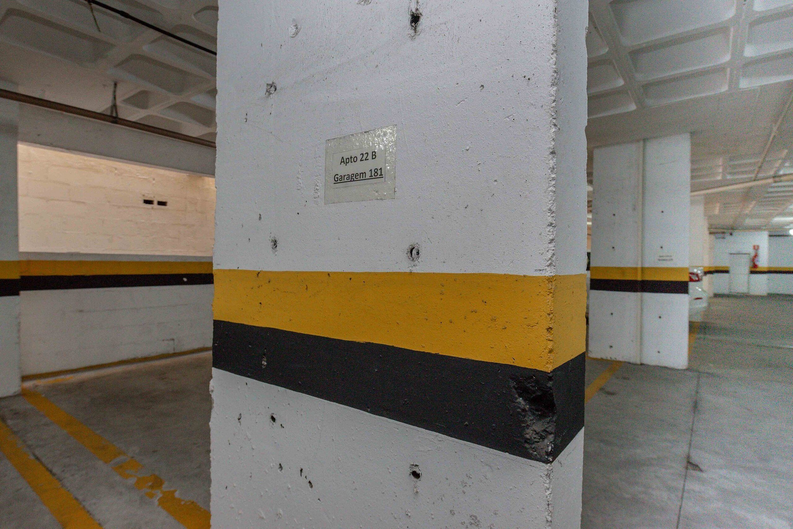 Un garaje para estacionar con paredes blancas, franjas amarillas y negras, y un letrero que indica el espacio de estacionamiento 22 B, garaje 181.