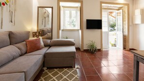Un salon comprenant un canapé, un pouf et un téléviseur à écran plat fixé au mur.