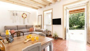 Un salon chaleureux avec une table à manger en bois, un canapé et un téléviseur fixé au mur.
