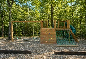 A playground with a climbing wall, swings, and a slide.