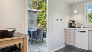A modern kitchen with a coffee maker, a sink, and a window overlooking a garden. - Amazing home in Jægerspris with kitchen (Jægerspris)