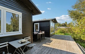 A wooden deck with a table and chairs, a small outdoor kitchen, and a view of the surrounding greenery. - Amazing home in Jægerspris with kitchen (Jægerspris)