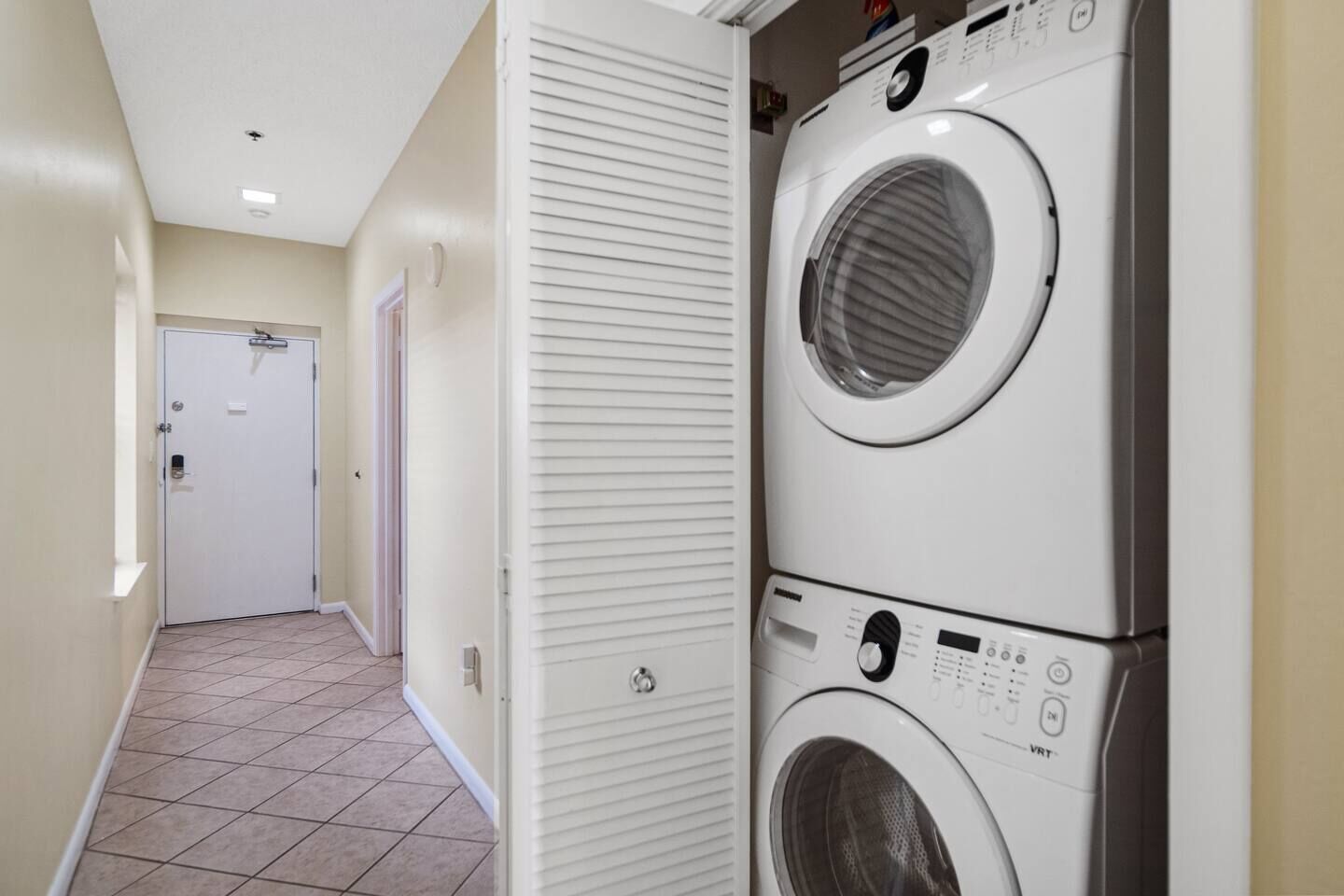 A laundry room with two stacked front-loading washing machines and a door in the background.