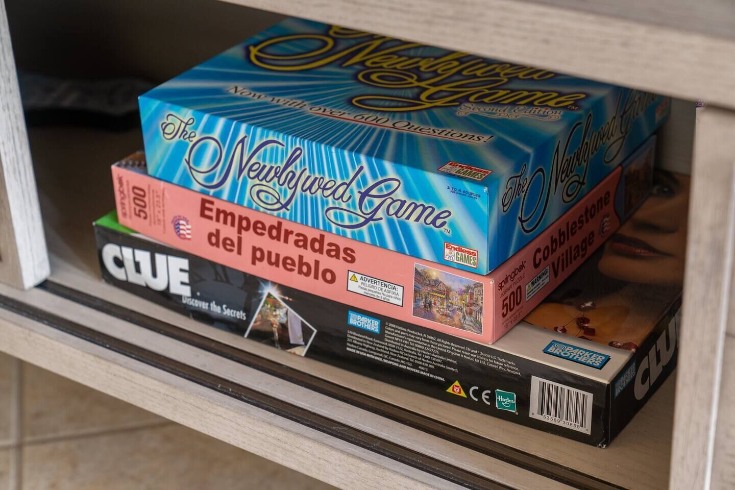 Dos juegos de mesa, 'The New Game' y 'Clue', sobre una estantería.