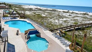 Ein Poolbereich mit zwei Pools, Liegestühlen und Blick auf den Strand.