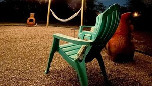 A green plastic chair and hammock under string lights at night. - 1 Acre Estate Across the Lake from LSU (Baton Rouge)