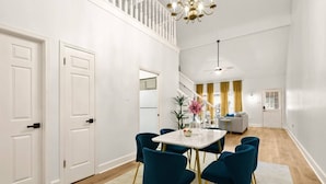 Uma área de jantar moderna com mesa de mármore branco, cadeiras verde-água e um candelabro.