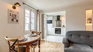 A modern living room with a grey sofa, wooden dining table with chairs, and a kitchen in the background. - La petite source: modern apartment in the heart of Honfleur (Honfleur)