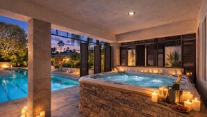 A hot tub with candles and a bottle of champagne, surrounded by stone walls and a pool. - Granada Hills Estate | Lap Pool, Spa & Guesthouse (Los Angeles)