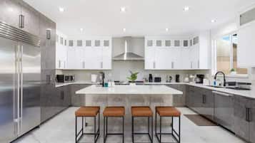 A modern kitchen with a central island, stainless steel appliances, and bar stools.