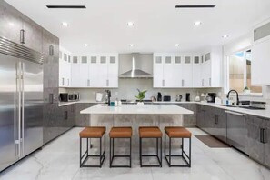 A modern kitchen with a central island, stainless steel appliances, and bar stools. - Granada Hills Estate | Lap Pool, Spa & Guesthouse (Los Angeles)
