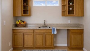 A kitchen with wooden cabinets, a granite countertop, a sink, and a window above the sink.