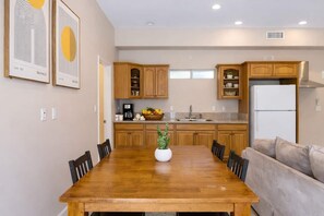 A modern kitchen with wooden cabinets, a dining table with chairs, and a refrigerator. - Granada Hills Estate | Lap Pool, Spa & Guesthouse (Los Angeles)