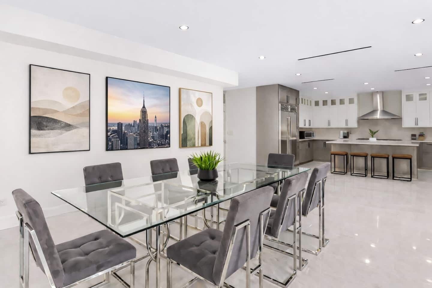 A modern kitchen with stainless steel appliances and a glass dining table with chairs.
