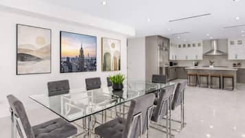 A modern kitchen with stainless steel appliances and a glass dining table with chairs.