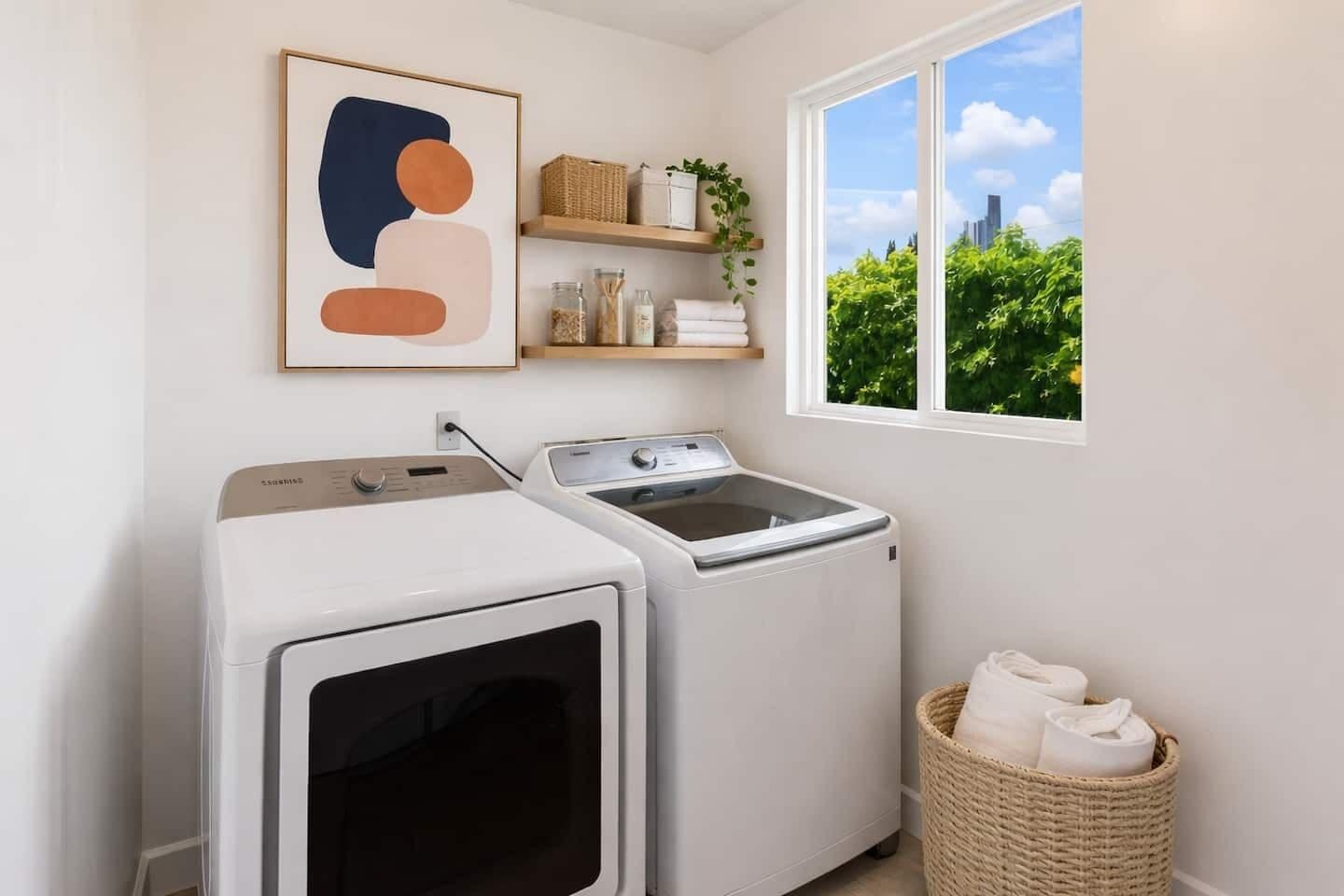 A laundry room with two washing machines, a drying rack, and a window with a view of greenery and a cityscape.