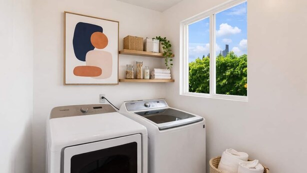 A laundry room with two washing machines, a drying rack, and a window with a view of greenery and a cityscape.