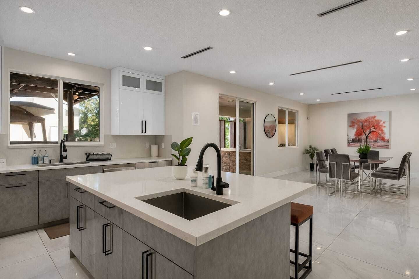 A modern kitchen with a central island, built-in cabinets, and a dining area with a table and chairs.