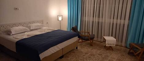 Una habitación de hotel con una cama, una silla, una mesita y una lámpara.