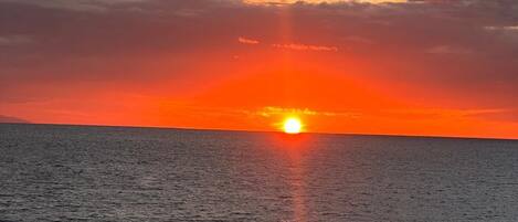 A sunset over a calm sea with a clear horizon.
