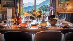 Ein Esstisch für vier Personen mit Blick auf die Berge, Holzwänden und einem Gemälde.