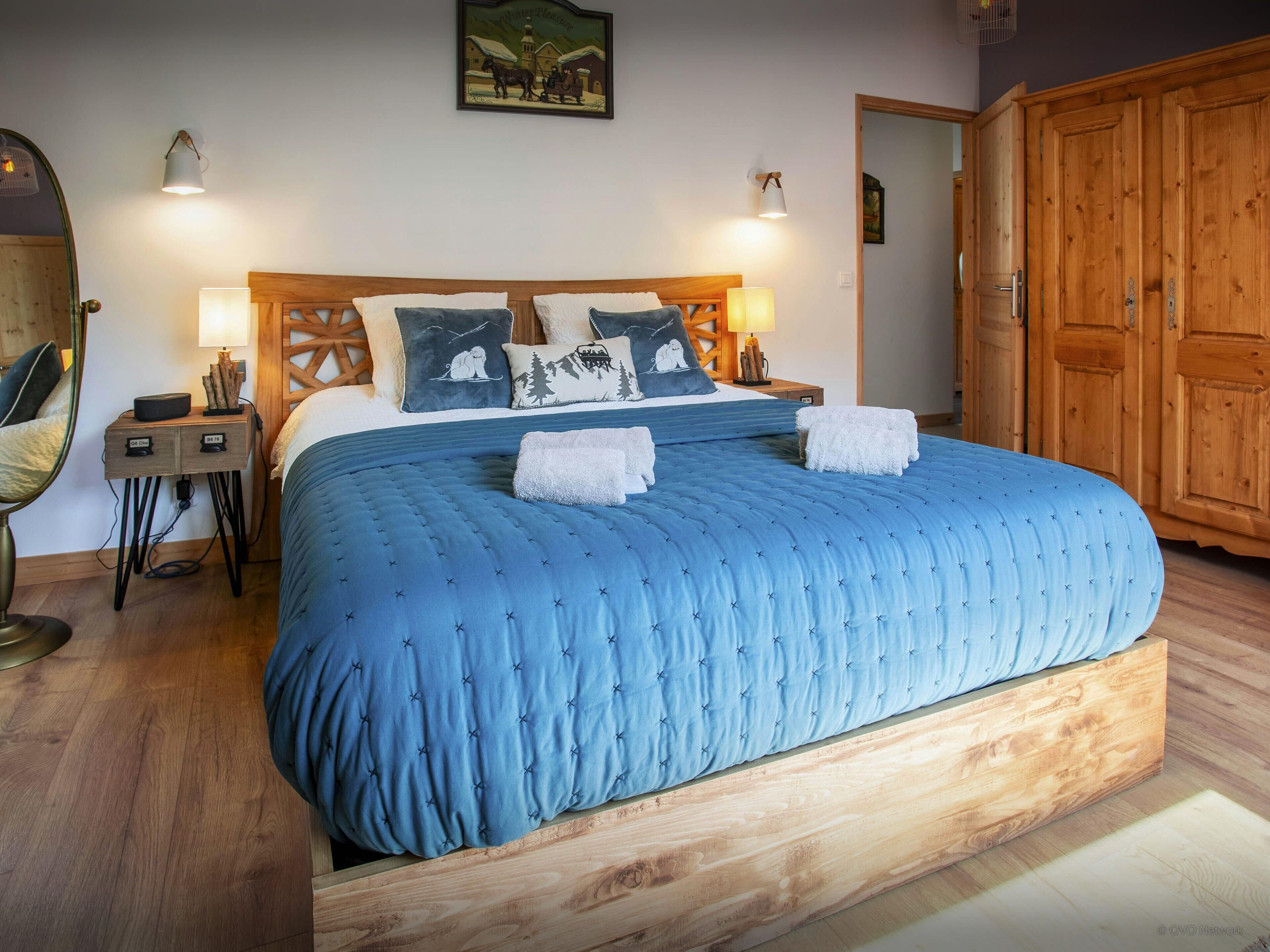 Een slaapkamer met een groot bed, een houten hoofdbord en twee nachtkastjes met lampen.