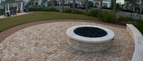 A circular brick patio with a central fire pit, surrounded by a curved walkway.