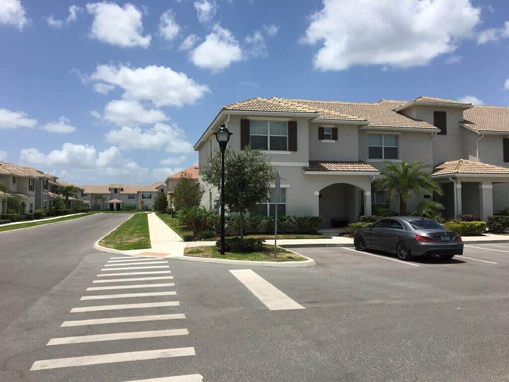 A residential street with a row of townhouses, a crosswalk, and a parked car.