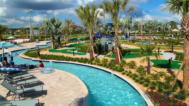 Uma piscina com espreguiçadeiras, palmeiras e um campo de golfe.