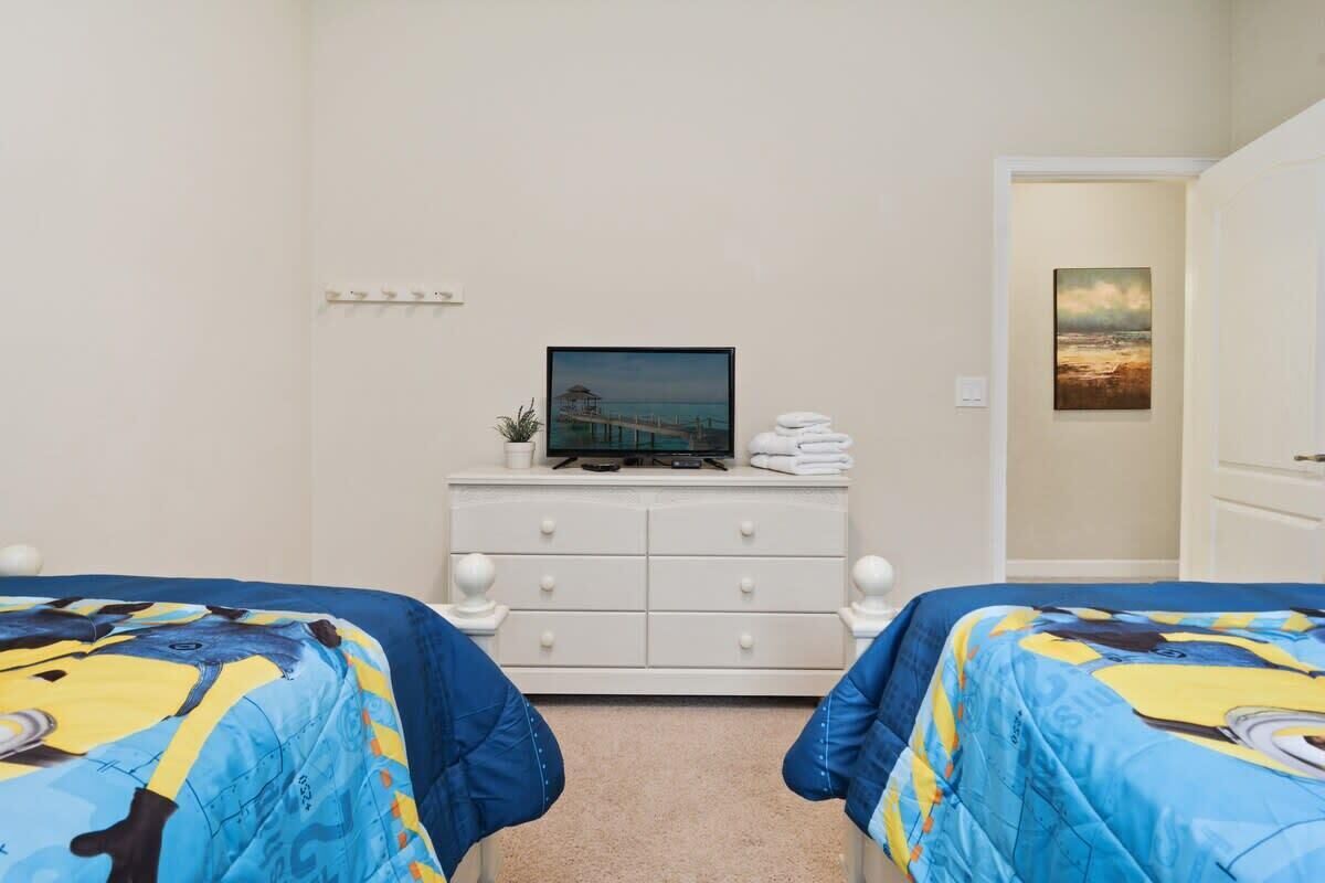 A hotel room with two beds, a TV on a dresser, and a painting on the wall.