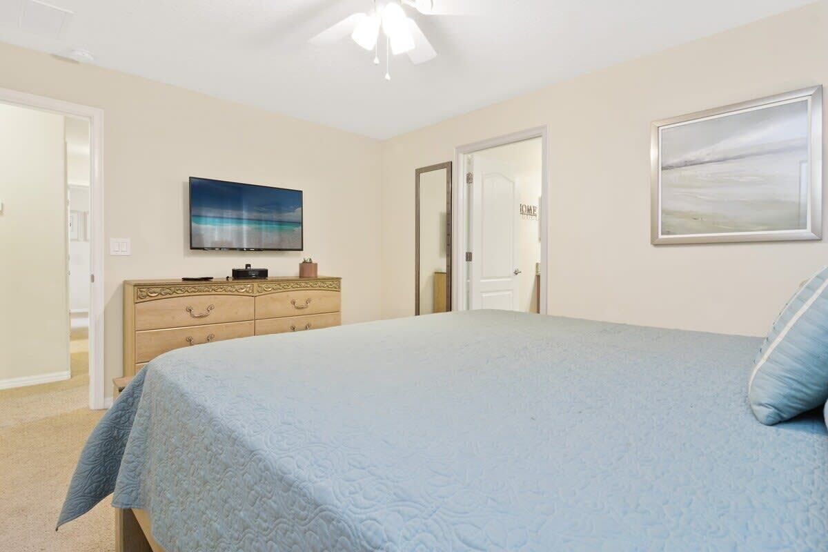 Een slaapkamer met een bed, een dressoir en een schilderij aan de muur.
