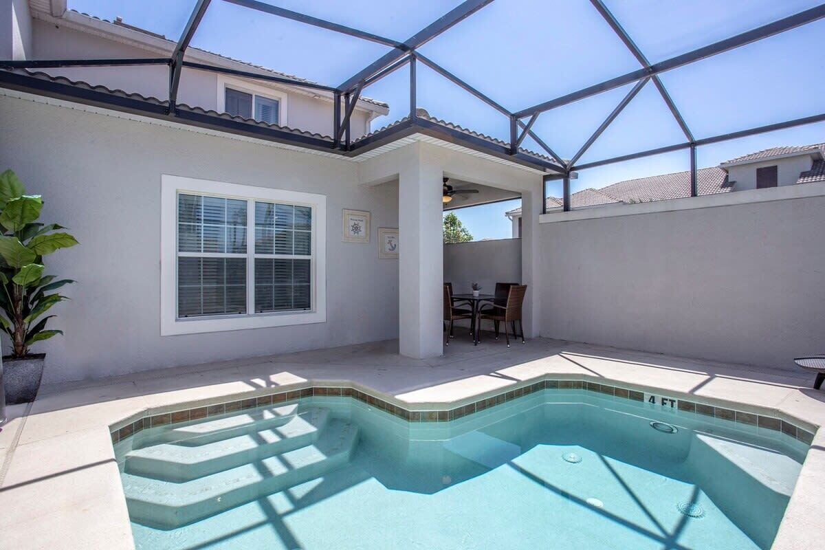 A swimming pool with a glass ceiling, a patio area, and a view of neighboring houses.