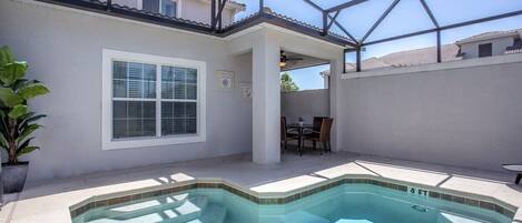 A swimming pool with a glass ceiling, a patio area, and a view of neighboring houses.